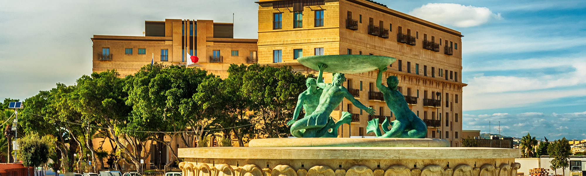 Malta - the Triton Fountain, trees and building in the background