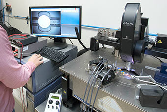 A researcher at a monitor and using equipment in a lab