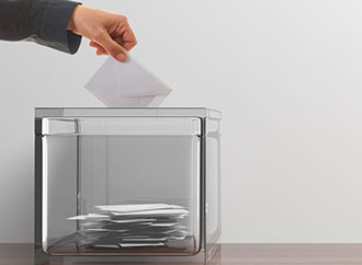 voter inserting envelop in box