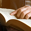 Person reading Holy Bible on blurred background