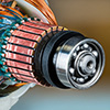 Closeup of ball bearing, commutator and rotor and stator inside electric DC motor. Copper wire with green epoxy in detail of machine to convert electrical energy into mechanical.