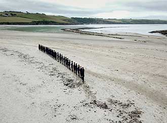 People in a curved line standing on the sand