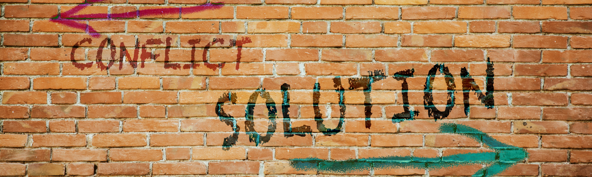 A brick wall with Conflict and Solution written on it. Conflict has an arrow pointing to the left next to it whilst Solution has an arrow pointing to the right.